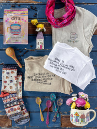Collection of home decor items including t-shirts, a mug, and decorative elements on a blue wooden surface.