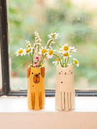 Two animal-shaped vases with flowers on a windowsill.