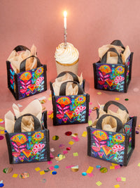 Colorful handbags with floral patterns on a pink background with a cupcake and candle.