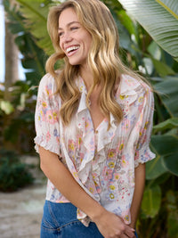 Woman wearing a floral blouse with plants in the background